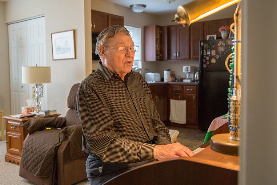 A man plays the piano in a cozy living room setting.