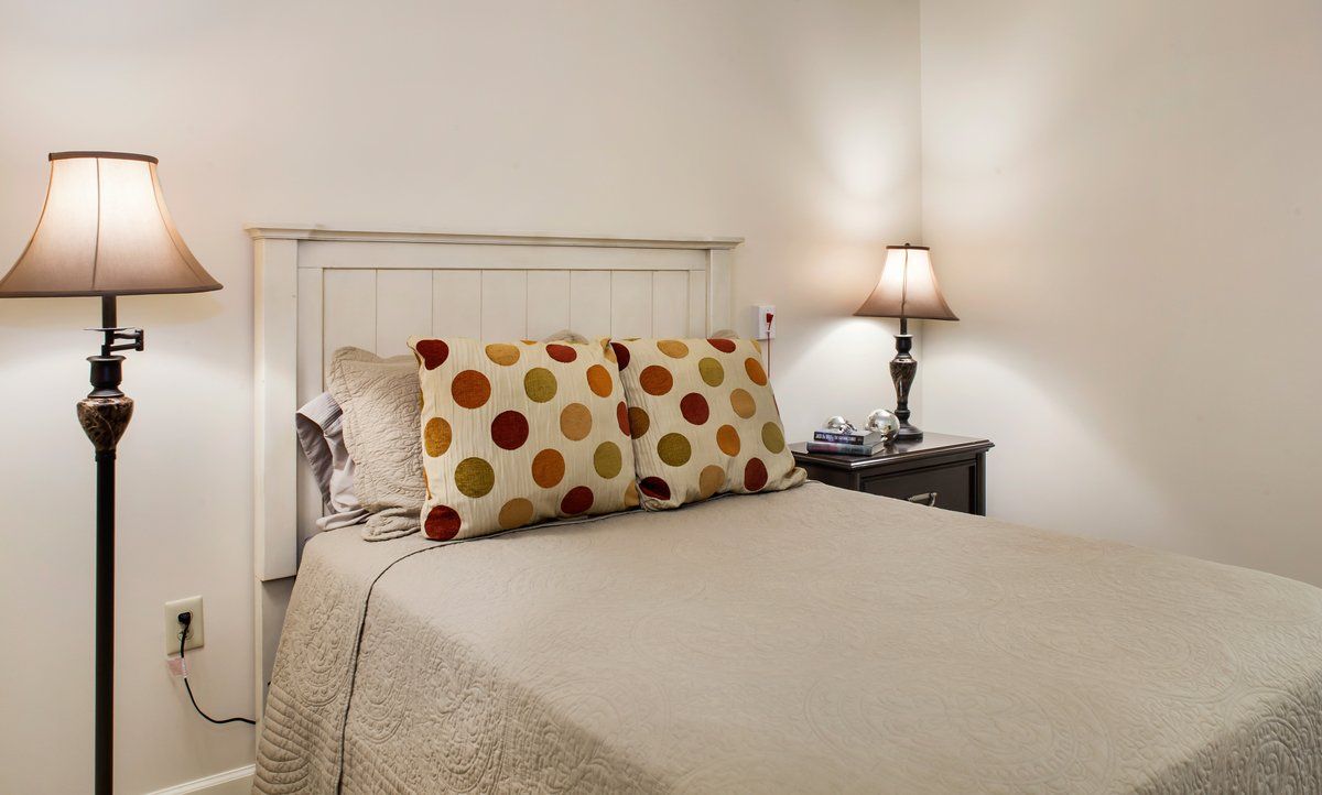 A cozy bedroom with decorative pillows and a bedside lamp.