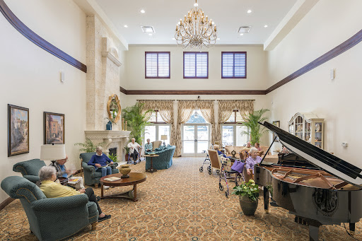 A spacious and elegantly decorated lobby with a chandelier, comfortable seating, and a piano.