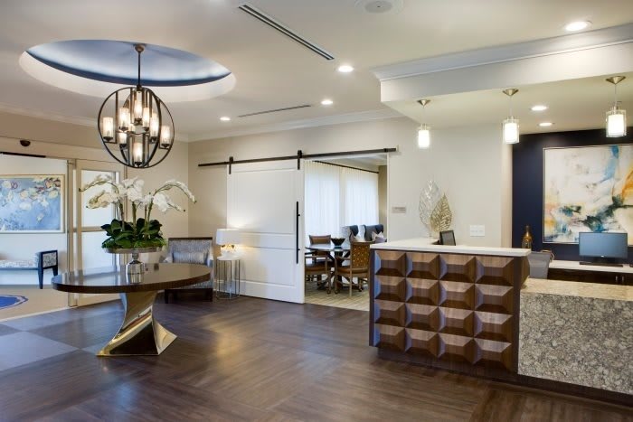 A modern reception area featuring contemporary decor with wood flooring and elegant indoor lighting.