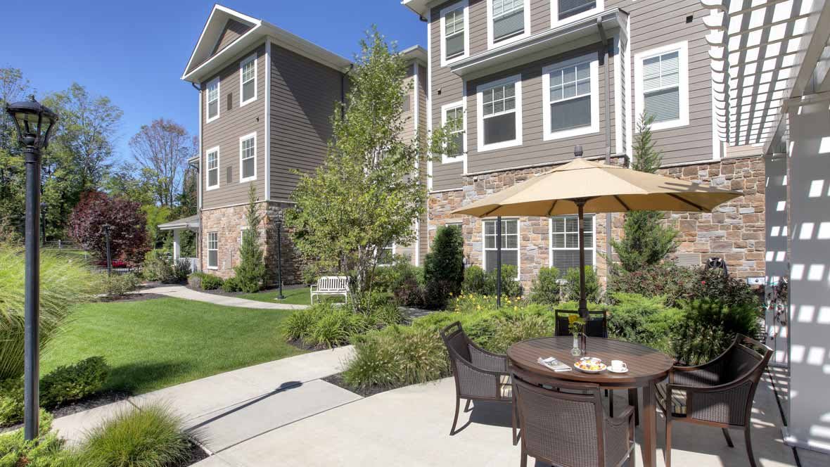 A modern apartment building with a well-maintained outdoor patio area featuring seating and an umbrella.