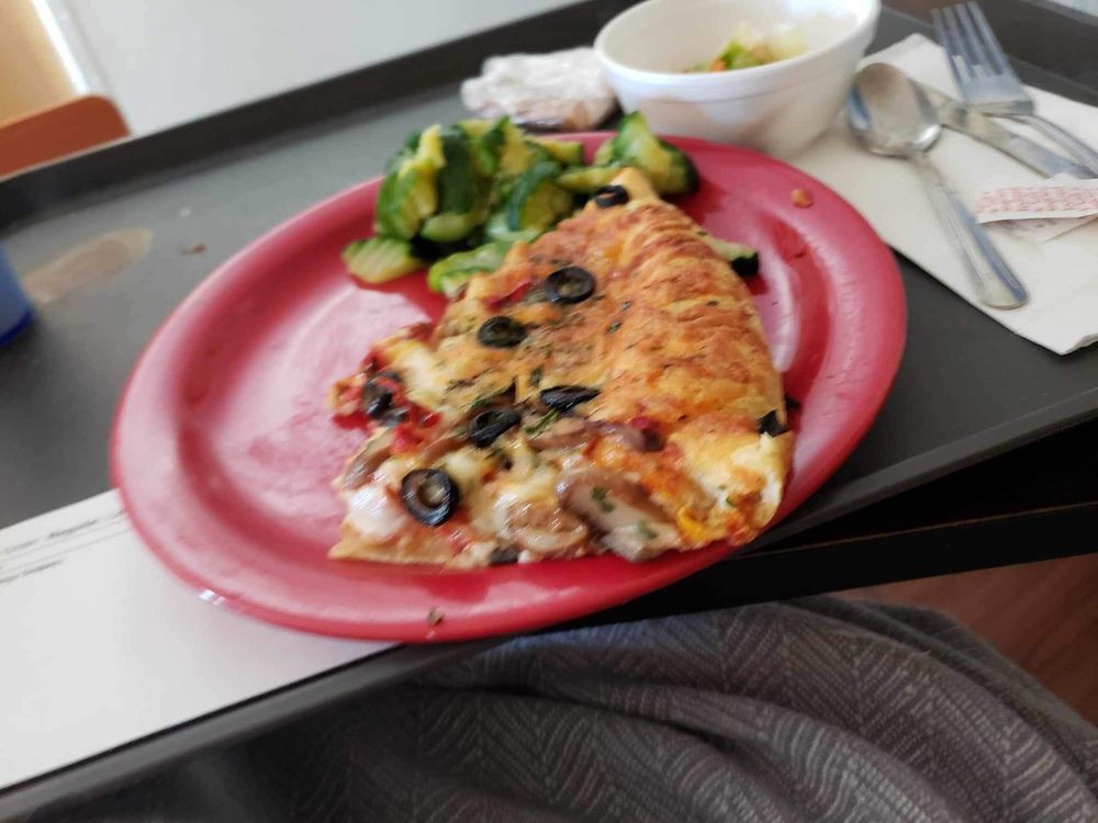 A tray with a slice of pizza and salad on a red plate.