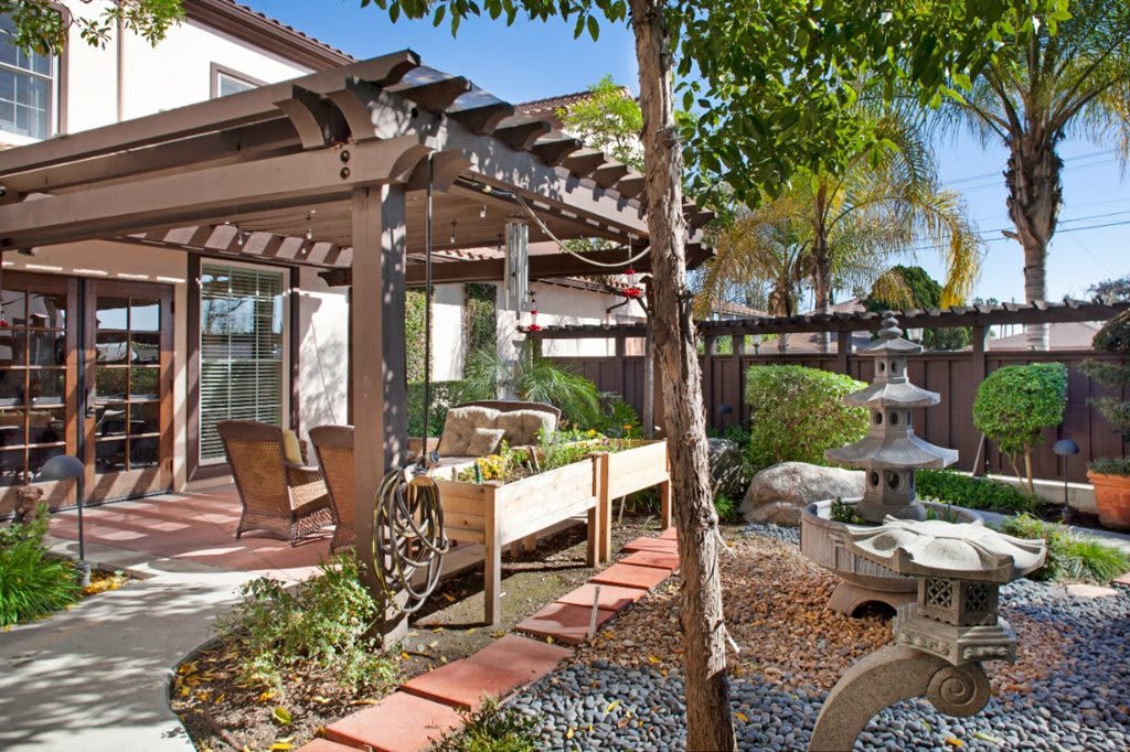 A serene backyard garden featuring a pergola and outdoor seating area.