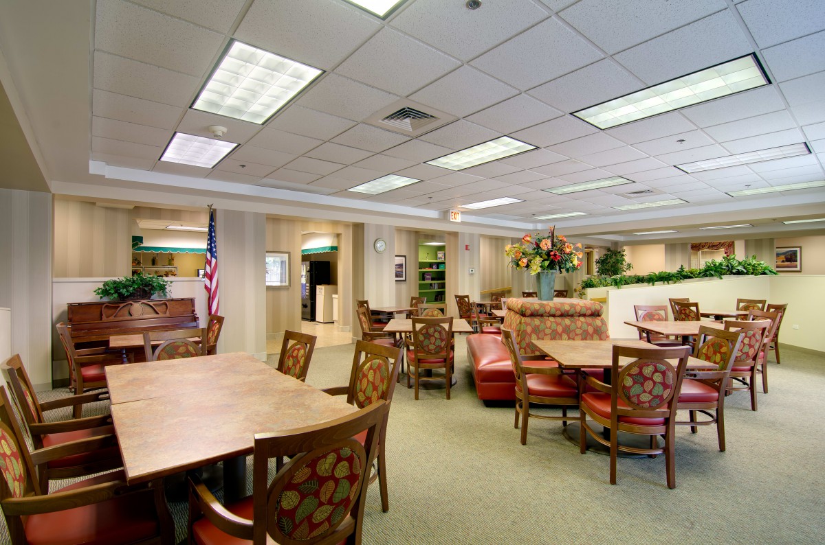 A spacious and well-lit lobby area with tables and chairs, an American flag, and decorative elements.