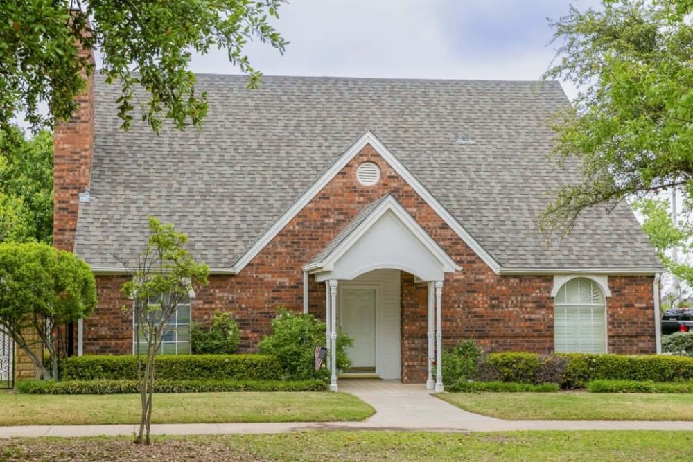 A suburban brick house with a neatly maintained front yard.