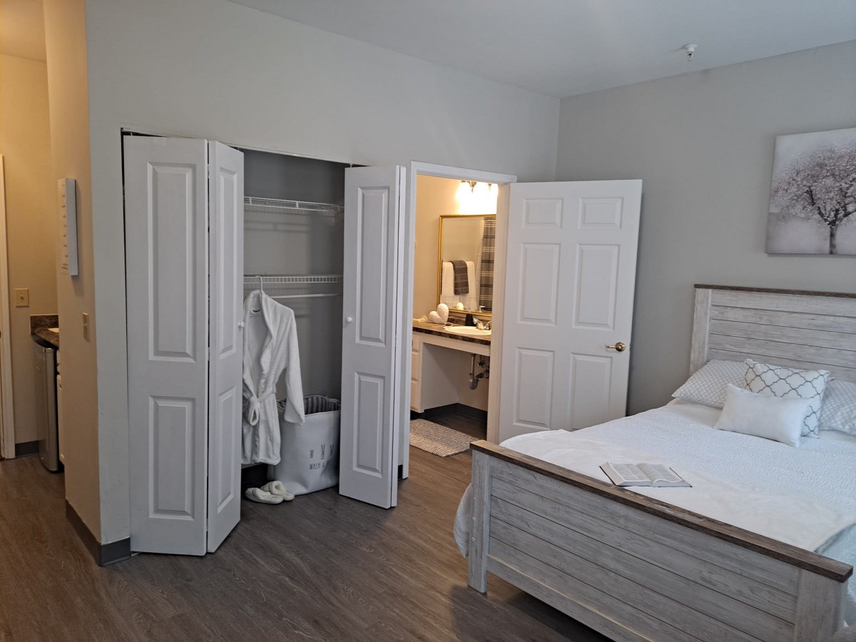 A cozy bedroom with an open closet and a view into the adjoining bathroom.