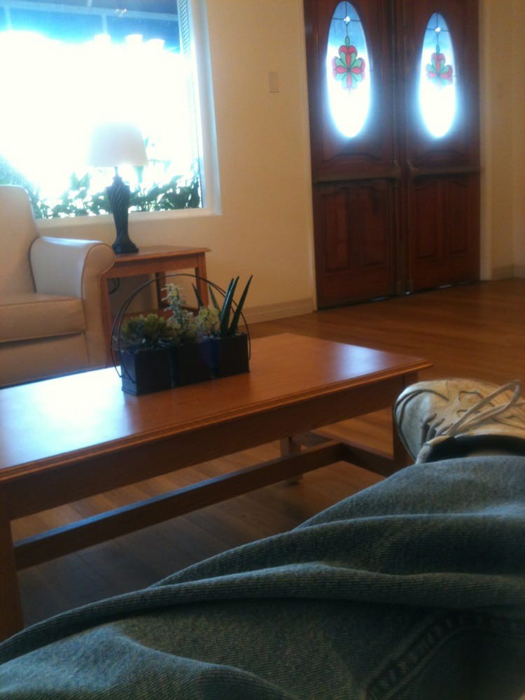 A cozy living room with a wooden coffee table, sofa, and indoor plants near a window.