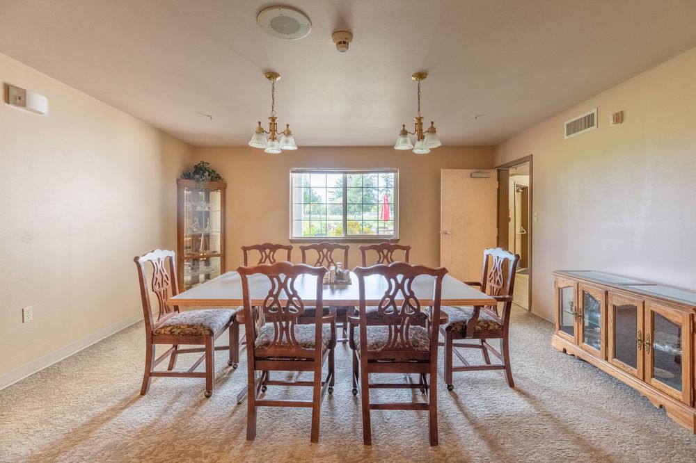 A traditional dining room with a large wooden table, surrounded by chairs and illuminated by chandeliers.