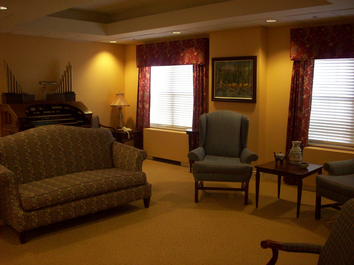 A cozy living room with a sofa, armchair, coffee tables, and decorative curtains.