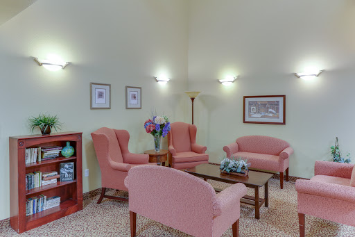 A cozy living room setup with soft pink chairs, a wooden coffee table, and decorative elements.