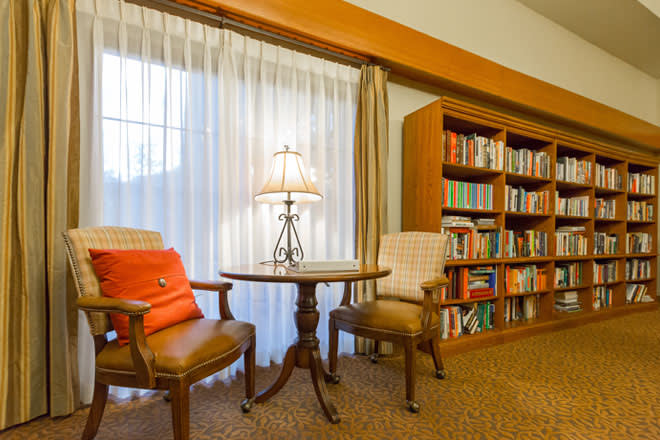 A cozy reading area with two chairs, a small table, and a well-stocked bookshelf.