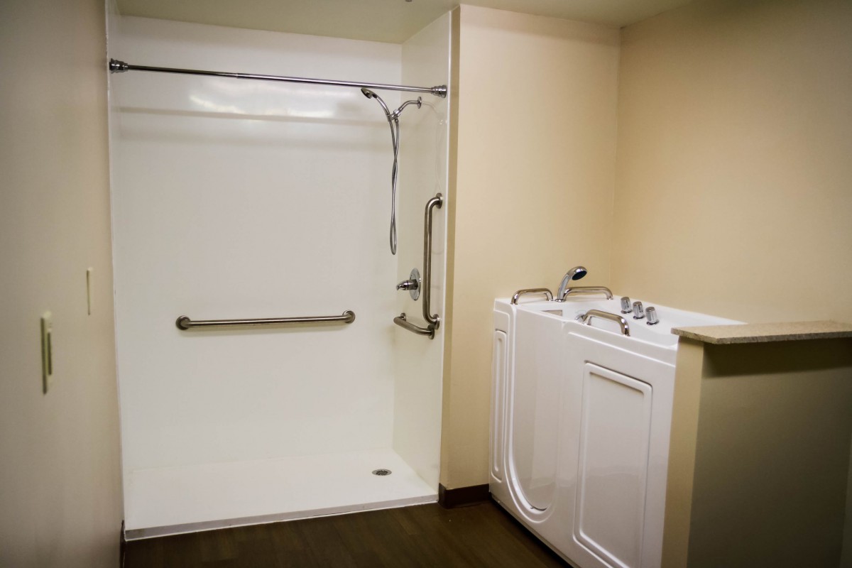 An accessible bathroom featuring a walk-in tub and a spacious shower with grab bars.
