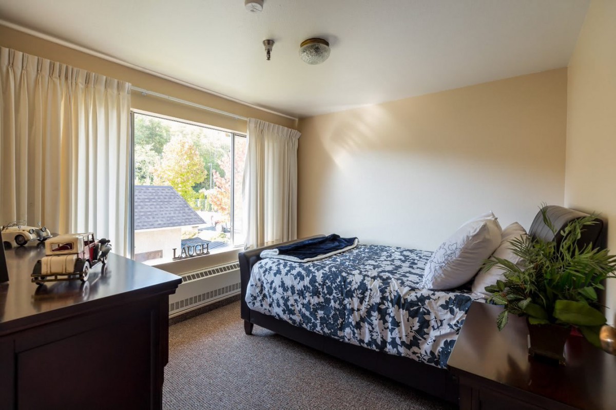 A cozy bedroom with a bed near a large window letting in sunlight.