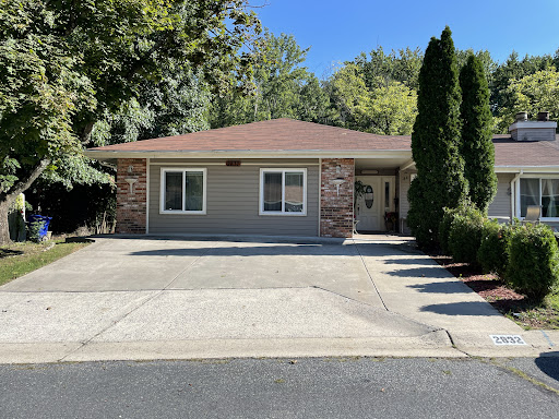 A charming single-story house with a well-maintained exterior and driveway surrounded by greenery.