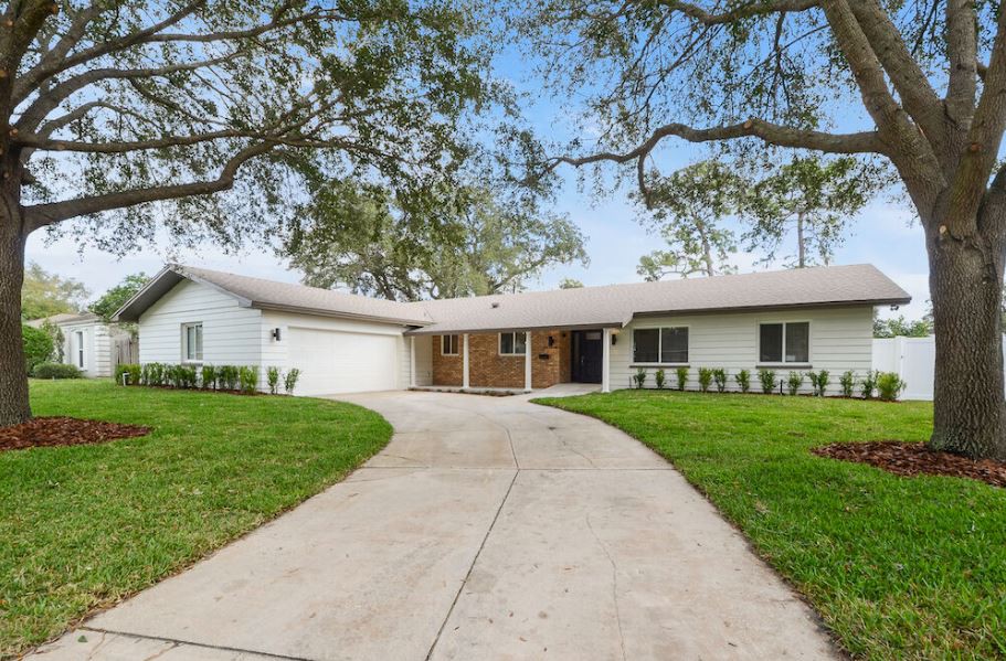 A single-story house with a curved driveway and a well-maintained front yard.