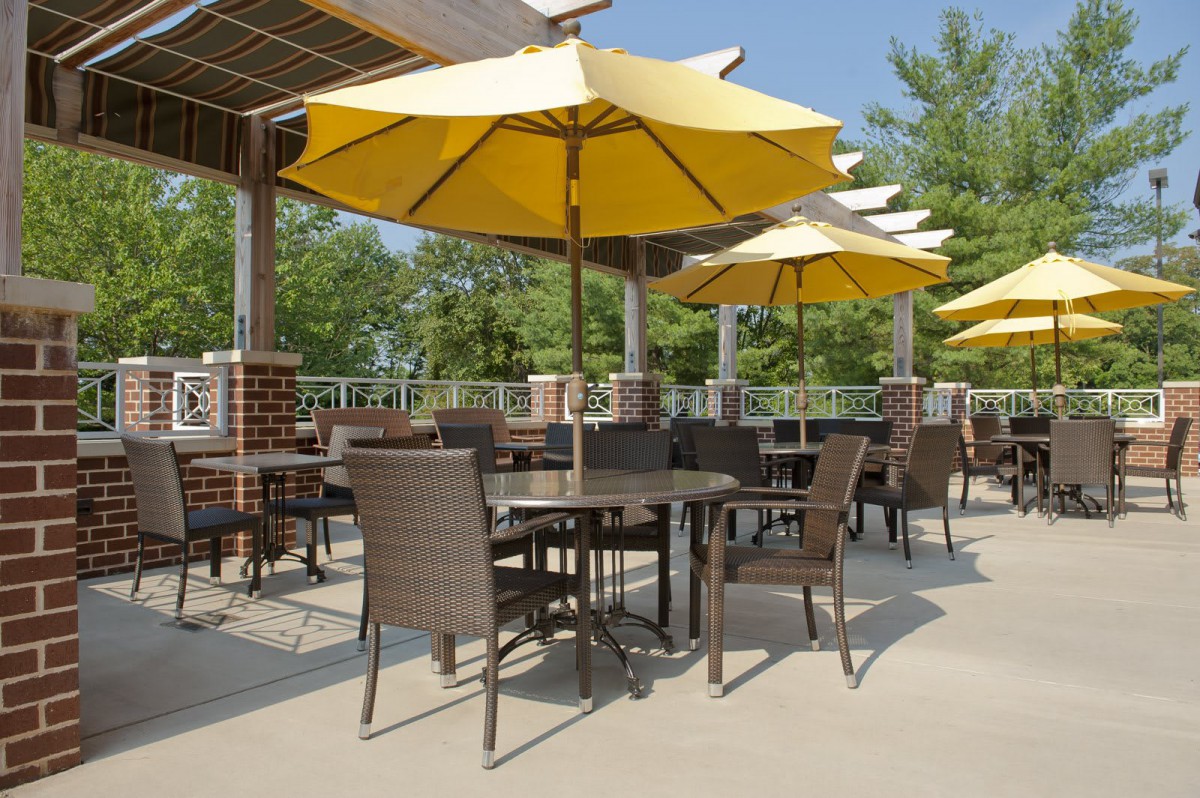 Outdoor patio with tables and yellow umbrellas on a sunny day.