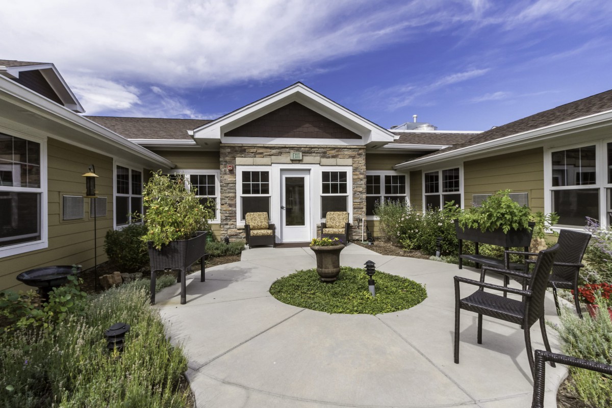 A well-maintained courtyard with outdoor seating and landscaping in front of a modern building.