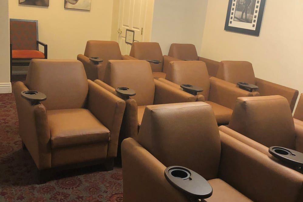 A cozy mini-theater with comfortable brown seats arranged in rows.