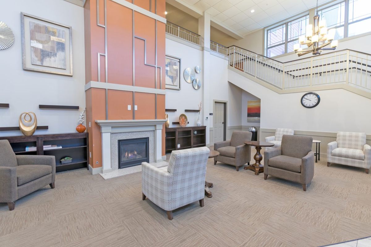 A modern living room with a fireplace, comfortable seating, and a staircase.
