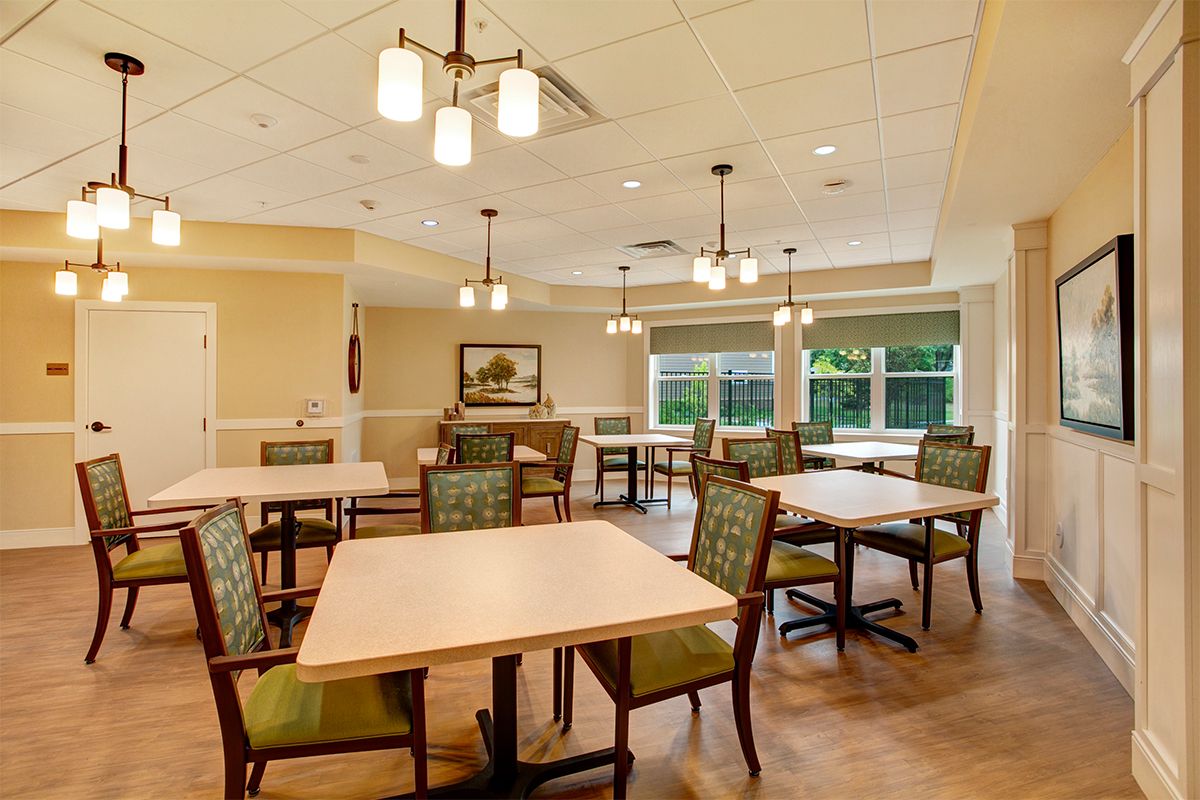 Spacious dining area with multiple tables and chairs, featuring elegant lighting and large windows.