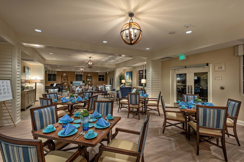 A spacious and elegantly designed restaurant interior with neatly arranged tables and blue napkins.