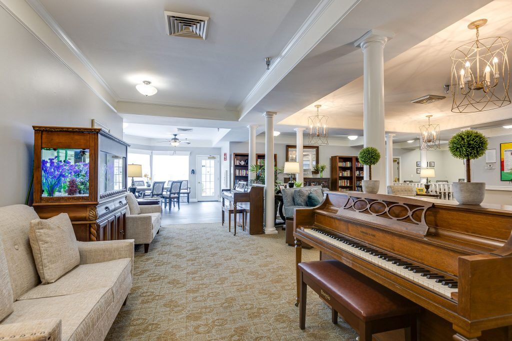 A cozy lounge area featuring a piano, comfortable seating, and bookshelves.