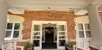 Entrance of a brick building with glass doors and potted plants.
