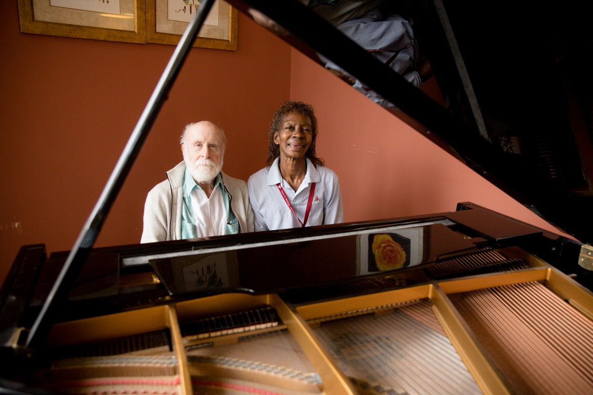 Two people sitting by a grand piano.