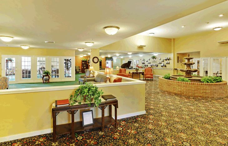 A spacious lobby interior with comfortable seating, decorative plants, and warm lighting.