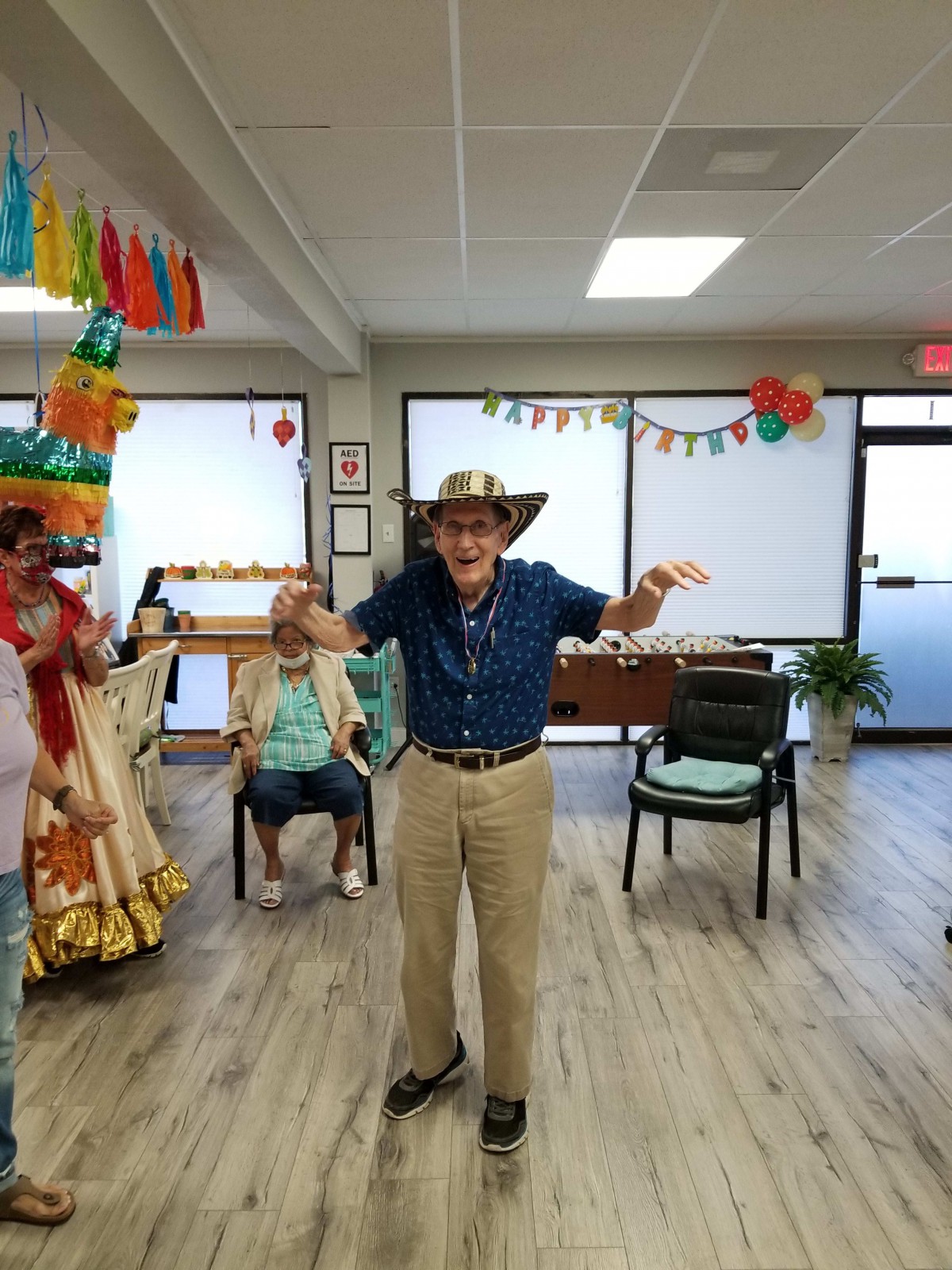 A joyful person wearing a hat celebrates indoors with festive decorations.