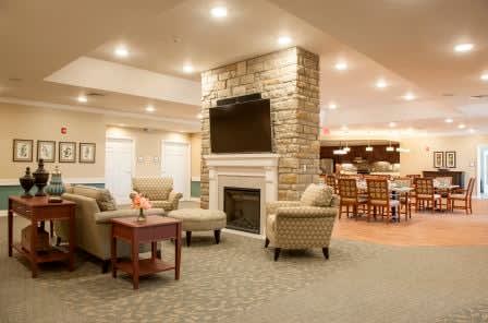 A cozy living room with a stone fireplace, comfortable seating, and a mounted television.
