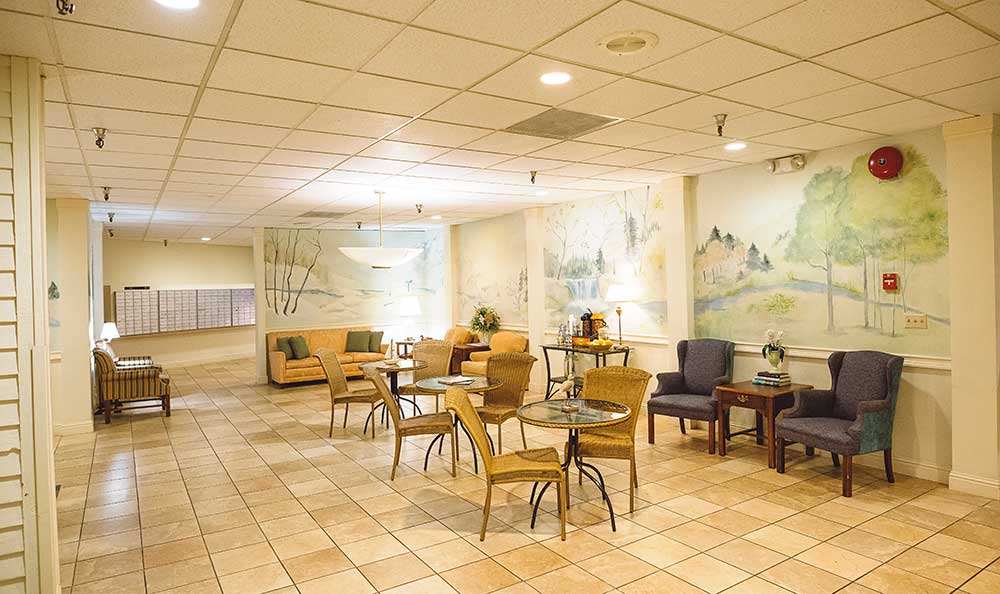 A cozy lobby with seating arrangements, featuring tables and chairs, decorated with artwork on the walls.