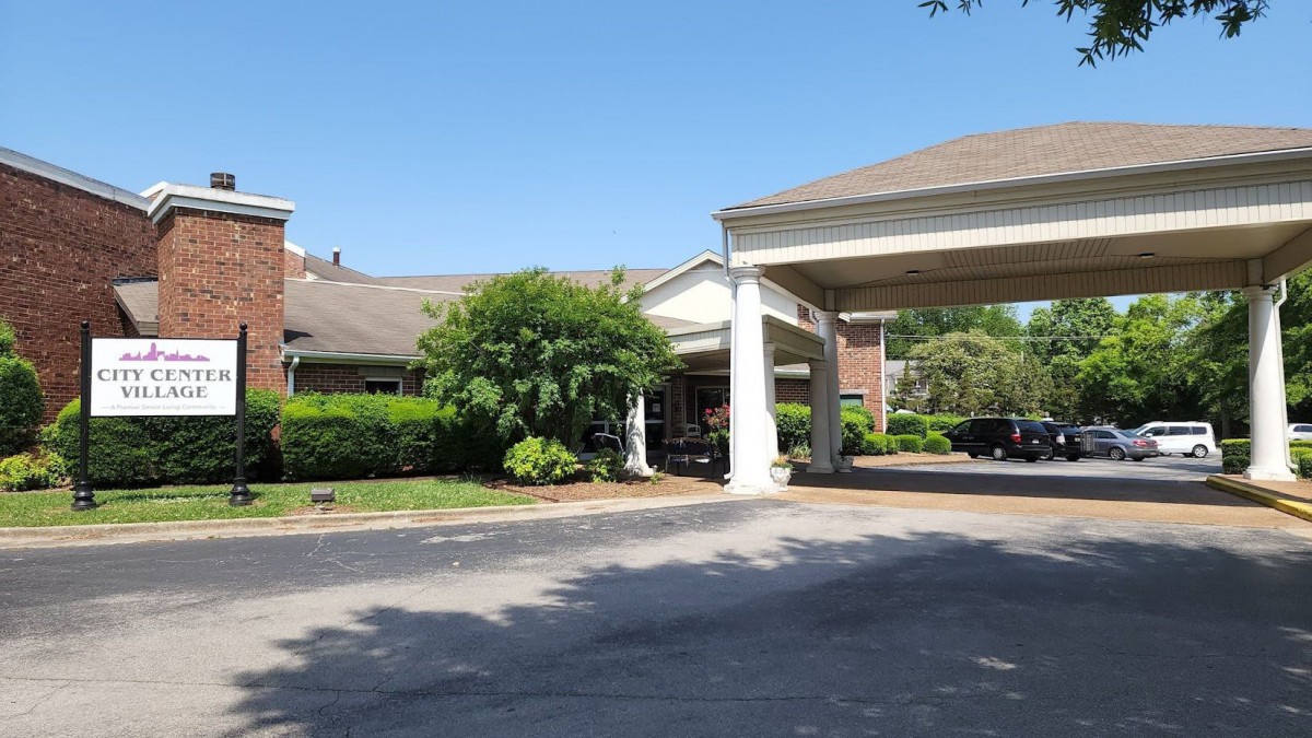 A hotel entrance with a covered driveway and landscaped surroundings.