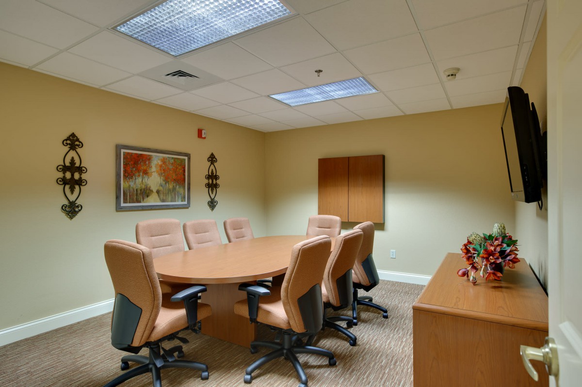 A well-lit conference room with a large meeting table and several office chairs.
