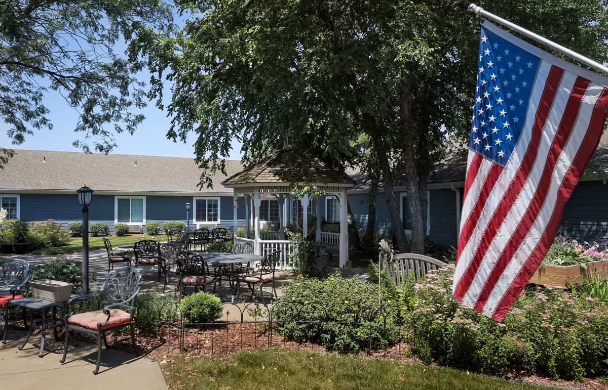 A peaceful garden patio with a gazebo and an American flag.