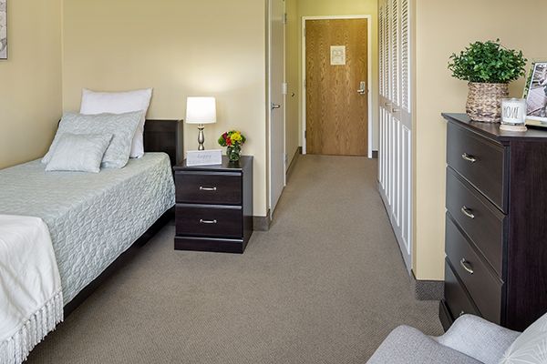 A comfortable and neatly arranged hotel room with a bed, nightstand, and soft lighting.
