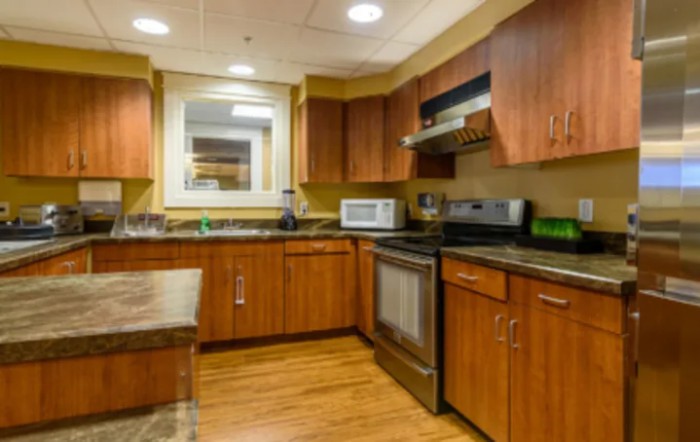 A modern kitchen featuring wooden cabinets, stainless steel appliances, and a granite countertop.