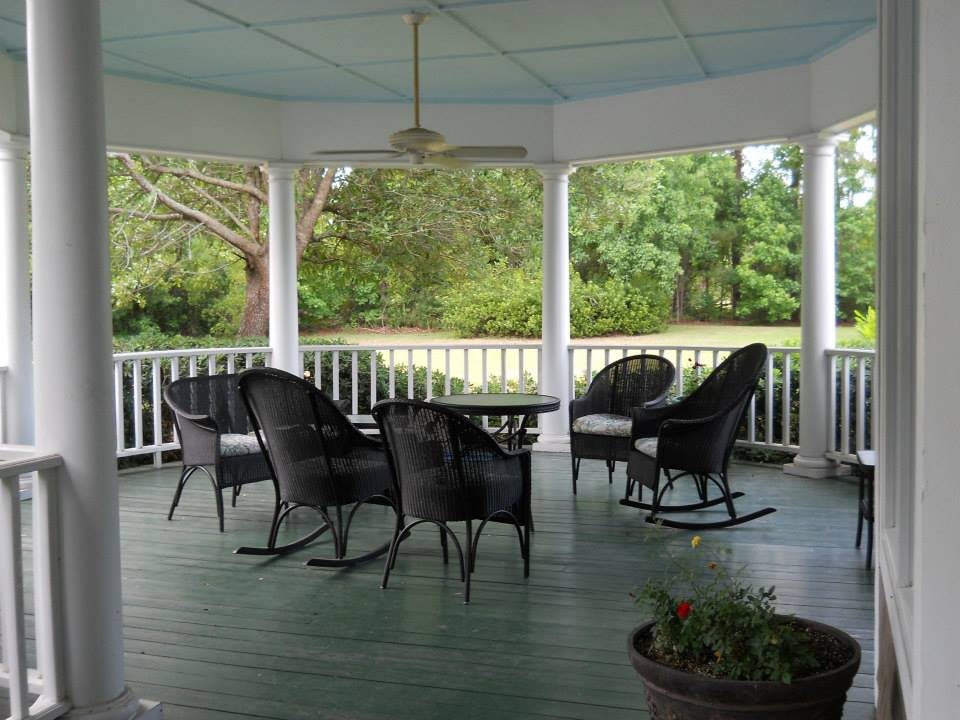 A peaceful gazebo with wicker chairs and a table, overlooking a lush garden.
