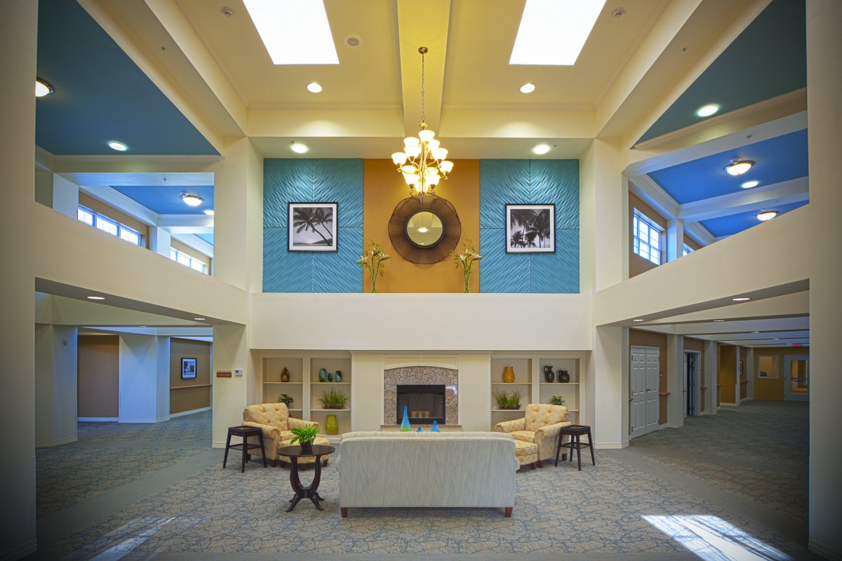 A spacious lobby with elegant interior design featuring a central chandelier, comfortable seating, and a fireplace.