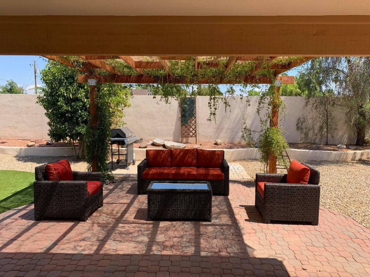 An inviting outdoor patio with a pergola, comfortable seating, and lush greenery.