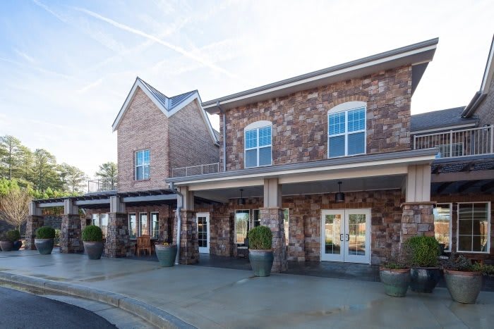 A two-story brick building with large windows and a paved entrance.