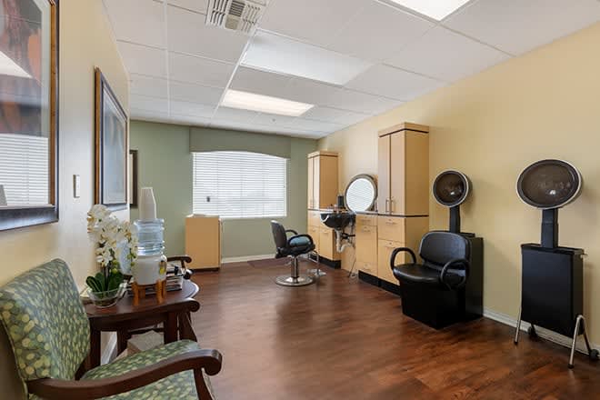 A well-lit hair salon interior with styling chairs, mirror, and hair dryer.