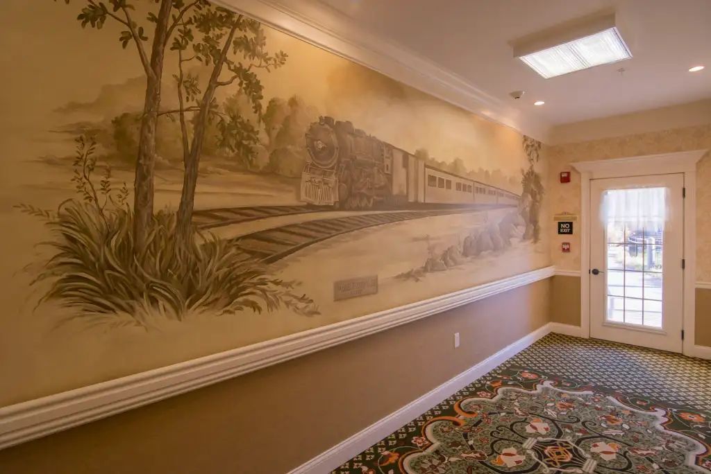 A sepia-toned mural of a train on the wall in a hallway.