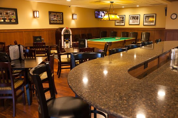 A cozy bar interior featuring a pool table, seating area, and a jukebox.