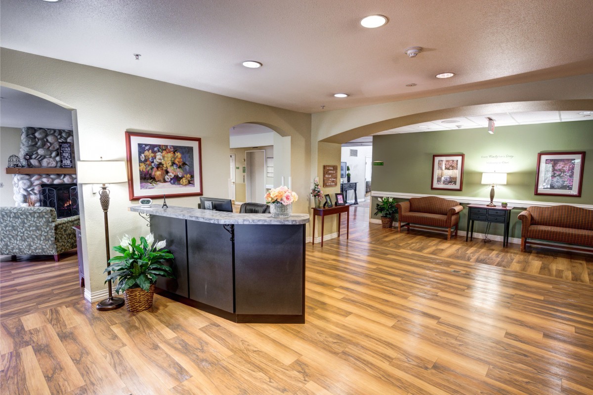 A modern office lobby with a reception desk, wooden flooring, and comfortable seating.
