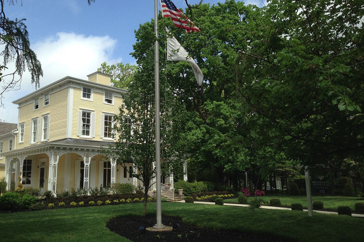 A historic house with a garden and flagpole featuring the American flag.