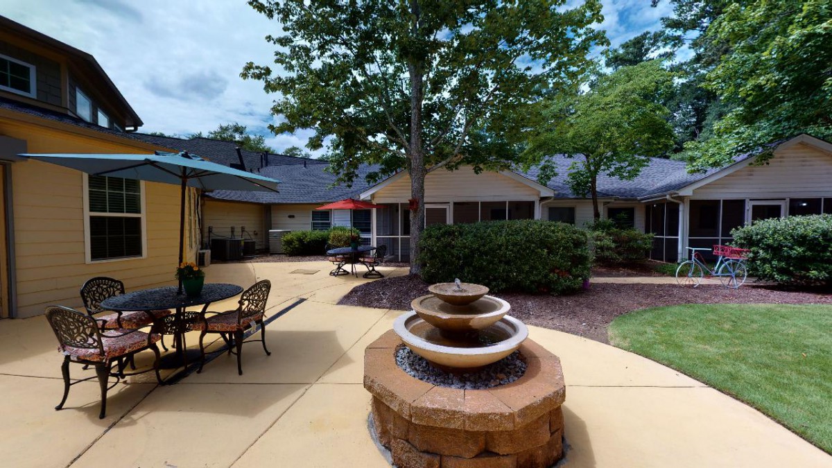 A tranquil outdoor patio featuring a central fountain surrounded by seating and lush greenery.