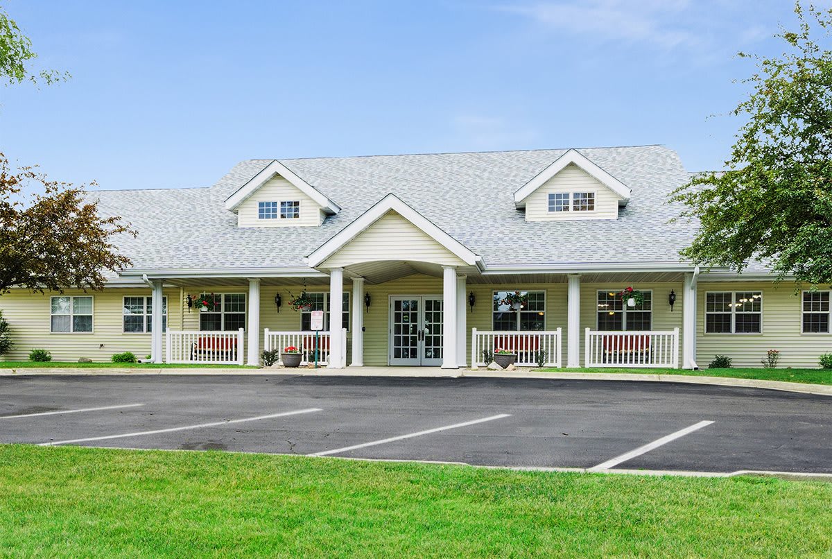 A large residential building with a front porch and well-maintained lawn.