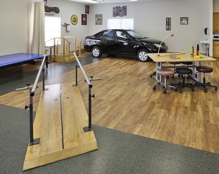 A rehabilitation center featuring a wooden ramp, exercise equipment, and an automobile for therapy purposes.