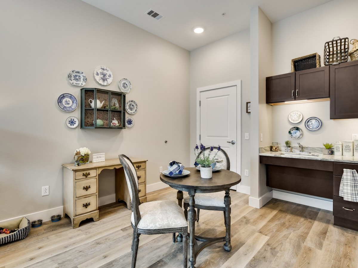 A cozy living area with an elegant table and chairs, a decorative desk, and wall-mounted plates.